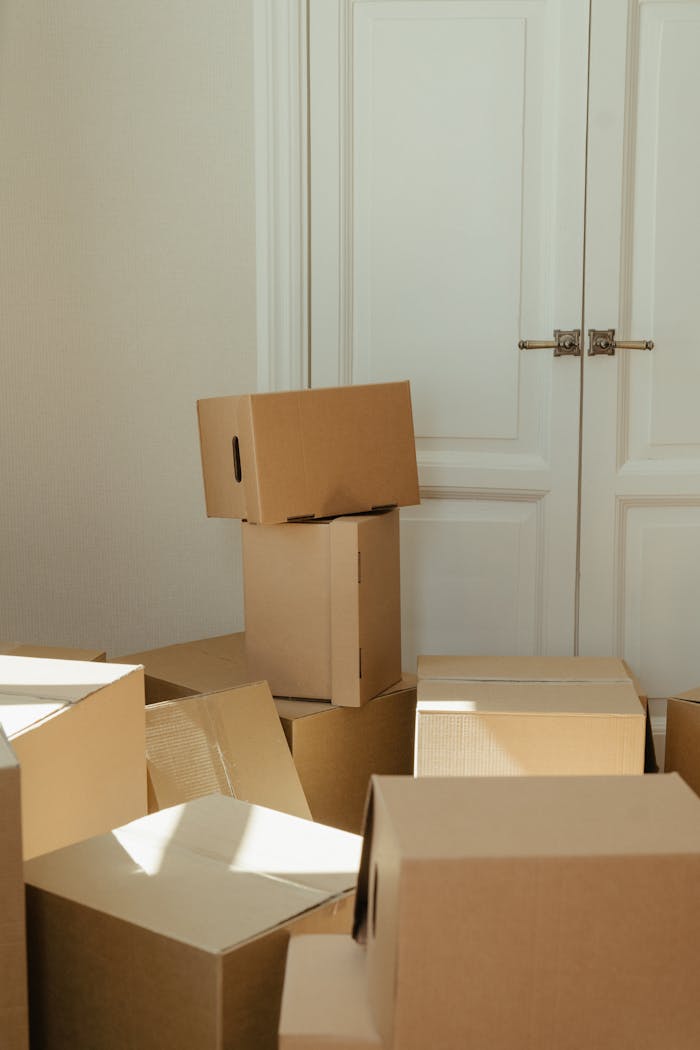 about-02 Stack of cardboard boxes by a white wooden door, perfect representation of moving day readiness.